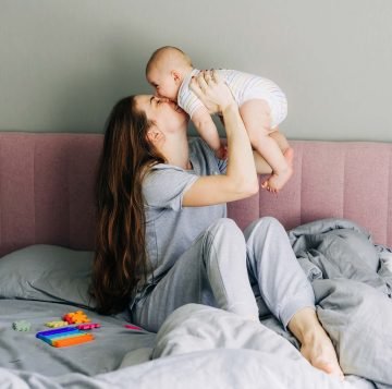 mom-holds-and-kisses-the-baby-caring-for-the-baby-LCCU6KC.jpg